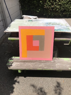 A work--in-progress photograph of an acrylic painting placed outside on an old picnic bench
